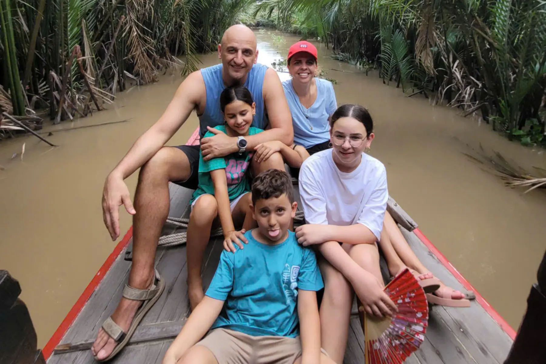 Family traveling by small boat through tropical canals in the Mekong Delta Vietnam