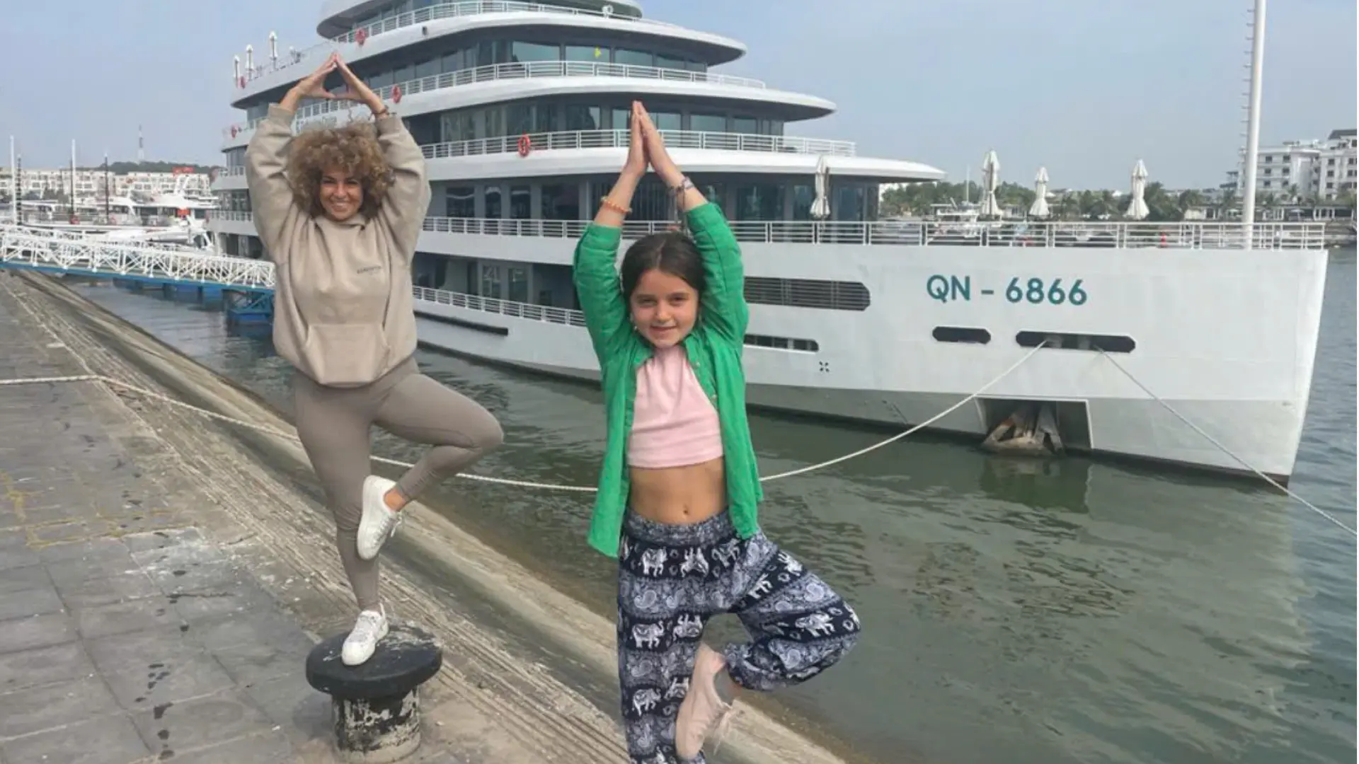Mother and daughter doing a yoga pose near a Halong Bay cruise ship in Vietnam